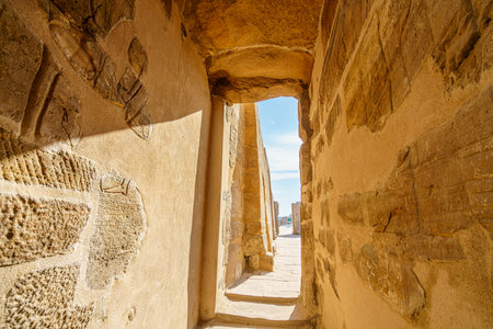 A sunlit narrow stone hallway inside the Temple of Karnak in Luxor Egypt. The carved walls and bright exit evoke history mystery and adventure.の写真素材