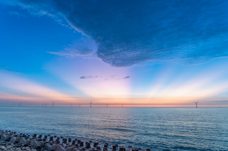 A breathtaking summer evening over the Miaoli coastline in Taiwan, featuring a stunning array of colors and wind turbines silhouette against the sky.の写真素材