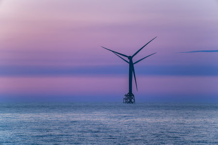 A spectacular twilight view of a stationary wind turbine in the sea, set against the beautiful, calm, and colorful sky.の写真素材