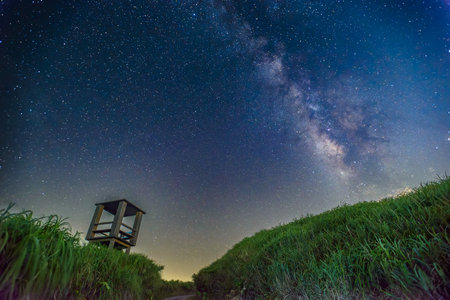 Stunning night sky time lapse of the Milky Way over an abandoned military Sentry Post on Wufenshan Shuangxi New Taipei Taiwan Lush green grass frames the view.の写真素材