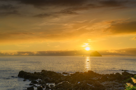 Experience a magical summer sunrise at Waimushan, Keelung, Taiwan. See fishing boats near Keelung Islet under an orange and golden dreamy sky.の写真素材
