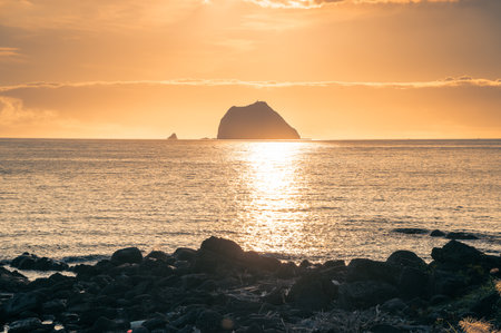 A spectacular summer sunrise over the Waimushan coastline in Keelung, Taiwan. The sky is painted with vibrant colors as the sun rises near the majestic Keelung Islet.の写真素材