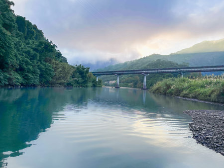 Serene early morning scene of Wulai River with clear turquoise water reflecting misty mountains and...