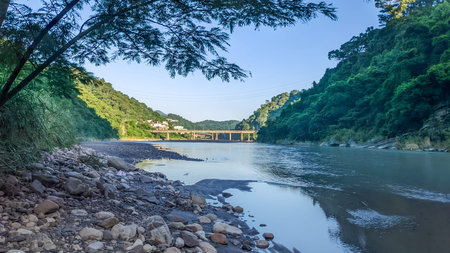 Rocky riverbank and clear water of a mountain stream in Wulai, New Taipei City, Taiwan. Lush green...