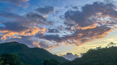 Intense orange and golden sunrise clouds glowing dramatically above the dark mountain ridges of Wulai in New Taipei City Taiwan at early dawn.の写真素材