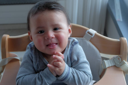 close up little cute boy smiling and claping his hands on the chairの写真素材