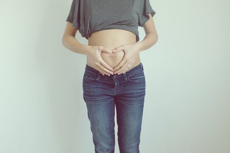 Woman showing heart on pregnant stomachの写真素材