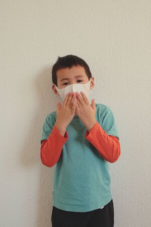 Young mixed race Thai-Swiss child boy wearing a mask isolated on white background. Virus protects concept idea. Coronavirus protection.の写真素材