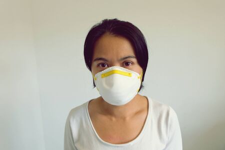 Young Asian woman with white shirt wearing a mask isolated on white background. Virus protect concept idea. Corona virus protection.の写真素材