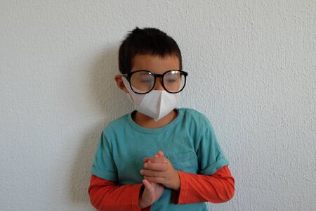 Young mixed race Thai-Swiss child boy wearing a mask and glasses isolated on white background. Virus protects concept idea. Coronavirus protection.の写真素材