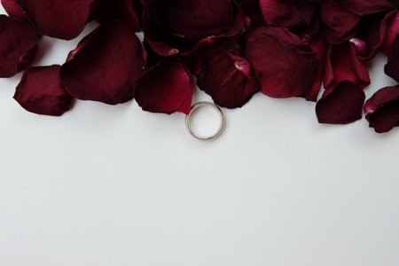 Wedding ring with dry rose petals isolated on white background.の写真素材