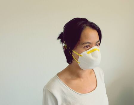 Young Asian woman with white shirt wearing a mask isolated on white background. Virus protect concept idea. Corona virus protection.の写真素材