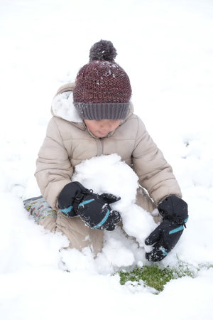 Portrait of happy cute kindergarten kid boy playing snow outdoor closeup.の写真素材