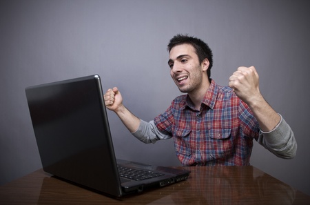  Joyful young man with laptop on gray backgroundの写真素材