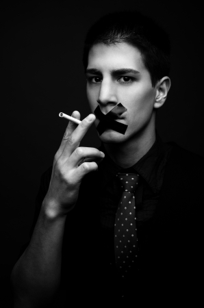 Young man struggling to quit smoking - low keyの写真素材