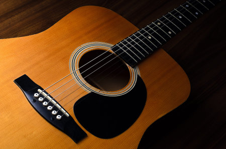 Close up shot of acoustic guitar on wooden table - low key
