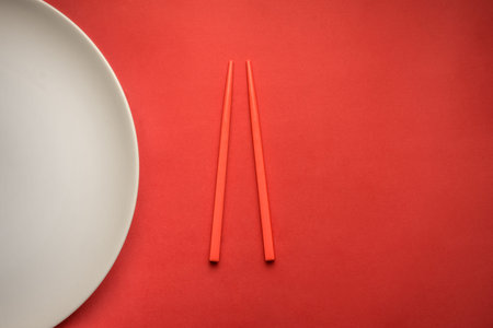 Chopsticks on red background with white plate.の写真素材