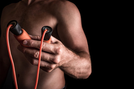 Adult caucasian male with skipping rope in his hands passing it to the viewer.
