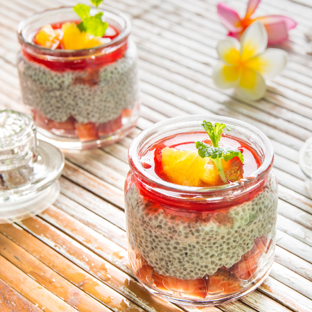 Chia seed and strawberry dessert in glass jar placed on tableの写真素材