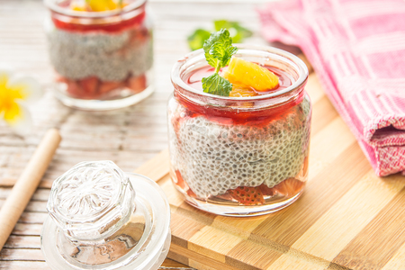 Chia seed and strawberry dessert in glass jar placed on tableの写真素材