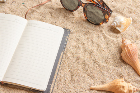 Daily planner on a sandy beach with shells and sunglasses.の写真素材
