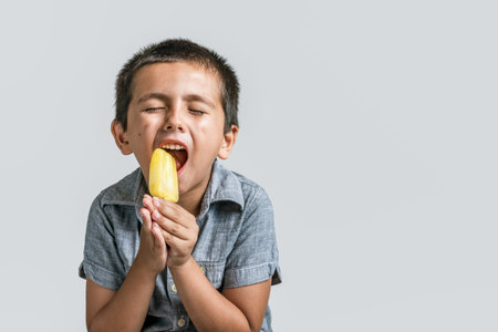 Little boy seriously enjoying his ice cream with funny expression and copy space for text.