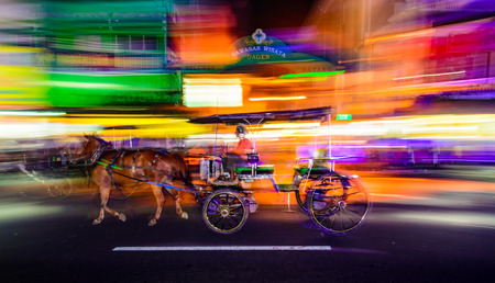 July 23 2015 - Maliboro Street Yogyakarta, Indonesia : Abstract panned image of a horse drawn cart commonly known as Andong or Dokar with colorful lights blurred across the frame.のeditorial素材