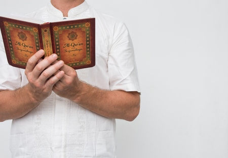 Man wearing white standing reading Al-Quran with copy space.の写真素材