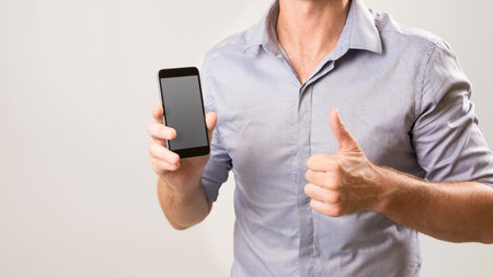 Man holding cell phone as if he is showing you something and giving the thumbs up. Casual business /...