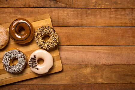 Different flavored doughnuts on wooden board with copy space for textの写真素材