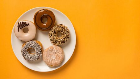 Doughnuts on plate with yellow background and copy space for text.の写真素材