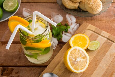 refreshing summer fruit drink with orange, lemon and mint on wooden benchtop.の写真素材