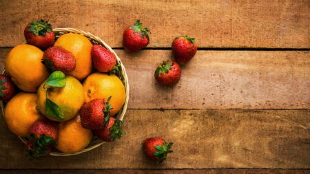Fresh organic oranges and strawberries on wooden table - flat lay healthy food concept image with copy space for text.の写真素材