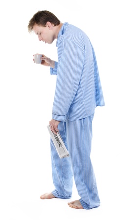 Very tired man in pajama s with newspaper and coffeeの写真素材