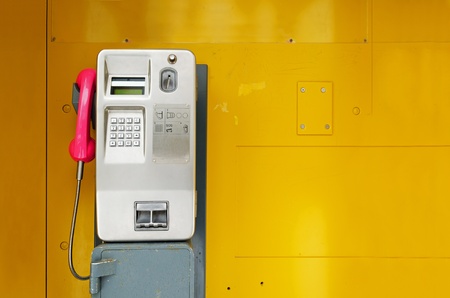 Old pay phone on yellow backgroundの写真素材