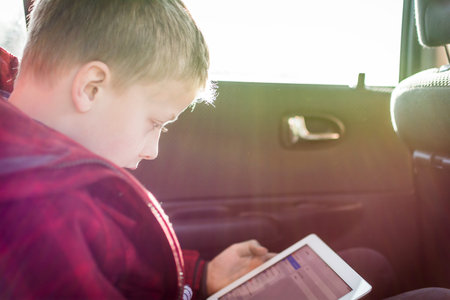 Boy in car on tablet pcの写真素材