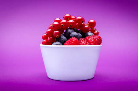 Assorted berries on a plate on pink backgroundの写真素材