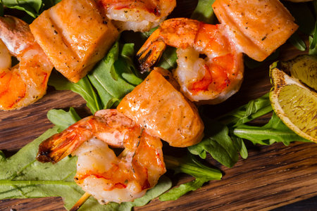 The shish kebab from shrimps and a salmon fried on coals with leaves of arugula and a limeの写真素材