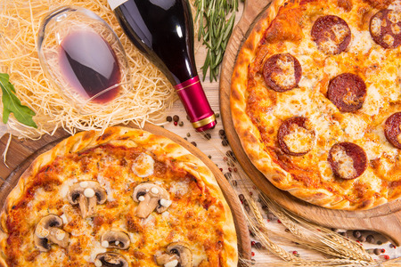Pizza of Pepperoni and Al Fungi's pizza with a bottle of wine and a glass of wineの写真素材