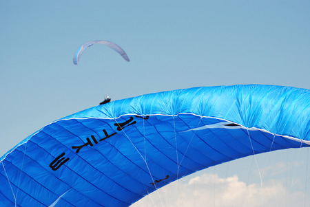 Blue paraglider on a background of blue cloudy skyの写真素材