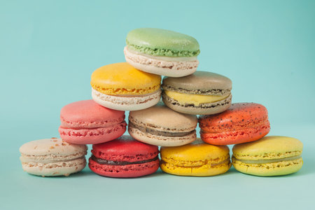 Pile of colorful macaroons stacked up like a tower in blue turquoise pastel isolated backgroundの写真素材