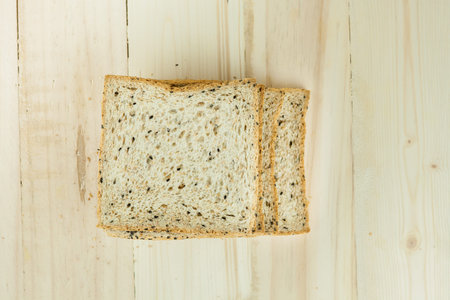 Fresh slices of wholewheat bread with various seeds and multigrain on wood background