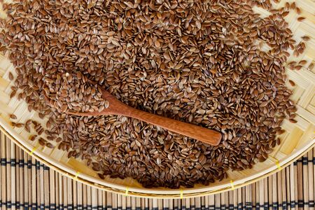 flax seed with spoon placed on flat woven basketの写真素材