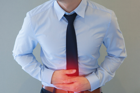 Man in office uniform having a stomachache / food poisoning / stomach problemsの写真素材