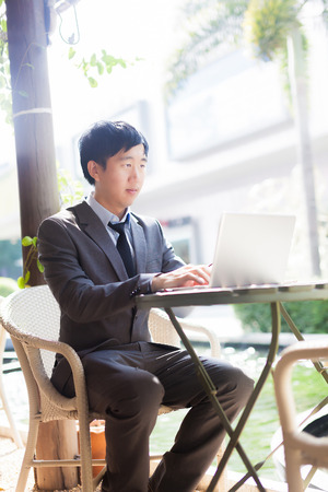 Young Asian businessman working with his laptop in outdoor sceneの写真素材