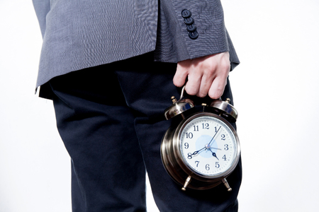 Man in Business Suit holding a clock - on time and business conceptの写真素材