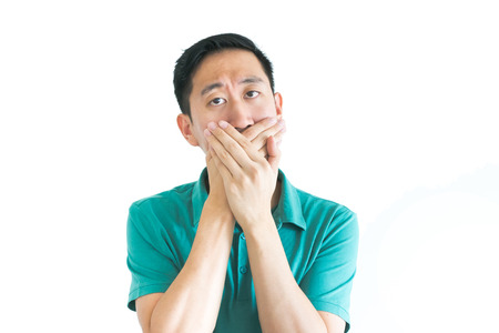 Young Asian man covering his mouth with handsの写真素材