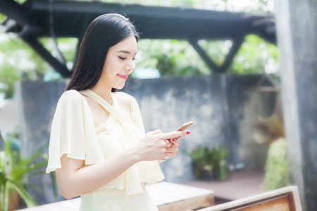 Beautiful Asian woman playing with her phoneの写真素材