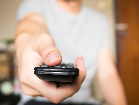 Close up of man pressing a button on remote control (shallow depth of field and focus on thumb)の写真素材