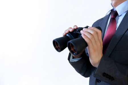 Close-up of Businessman looking for something with binoculars such as business opportunities / jobs / new market - business issues discovery concept.の写真素材